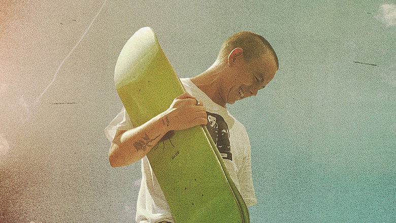 Leo Baker mid-trick, suspended in the air, the cityscape blurred in the background