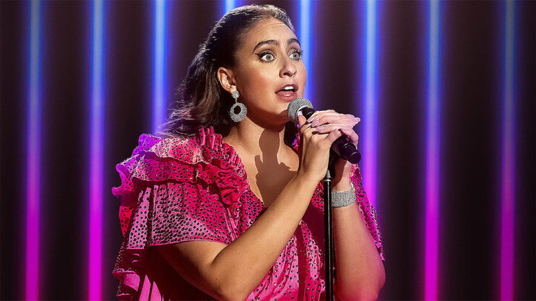 Catherine Cohen on stage, bathed in pink light, mid-song, her arms outstretched as if inviting the audience into a secret