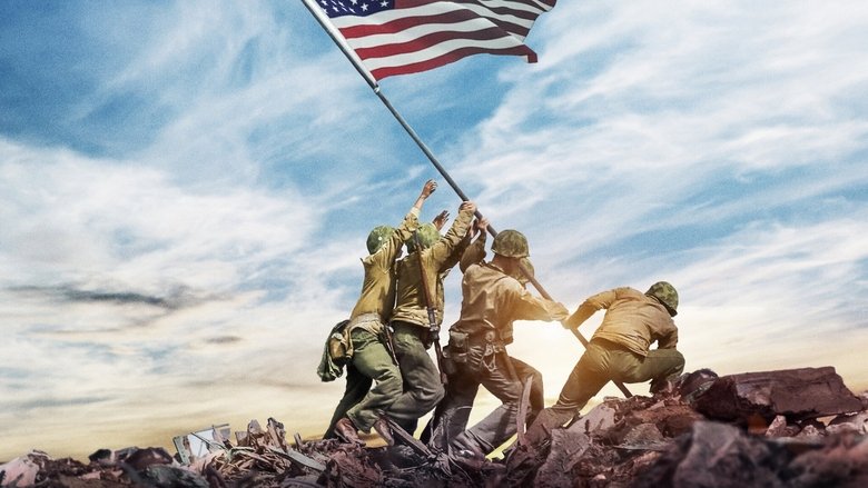 A colorized still of soldiers advancing through a war-torn European village, the rubble and uniforms rendered in muted but distinct hues.