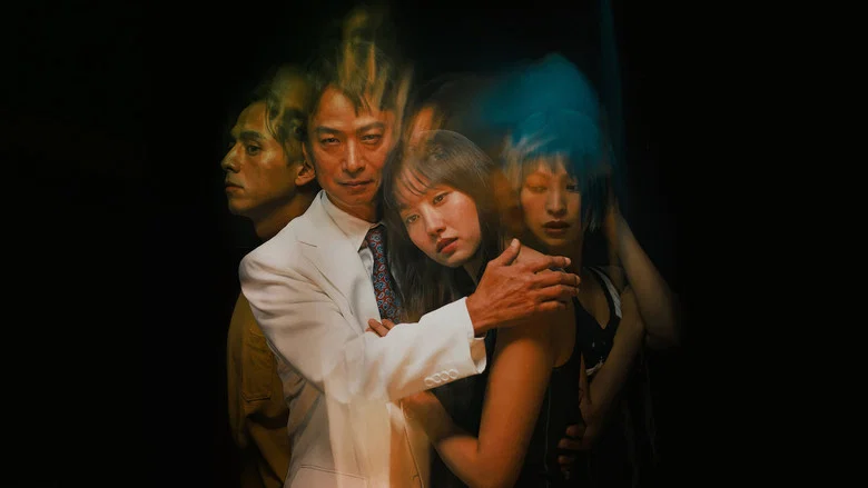 A dimly lit room where a group of young people sit in uneasy silence, their faces half-shadowed, as a charismatic older man looms over them with a grin that doesn’t reach his eyes.