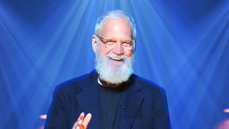David Letterman sits in a dimly lit studio, his face half in shadow, watching a comic perform with an expression that’s equal parts amusement and something like sorrow.