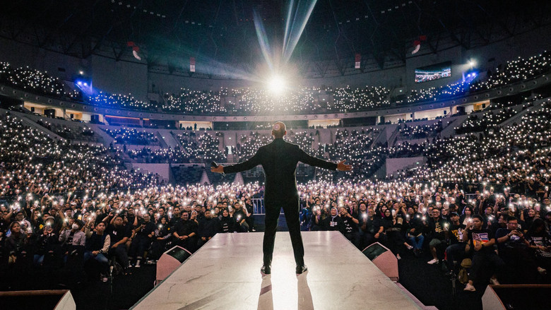 A wide shot of the massive arena crowd, bathed in blue light