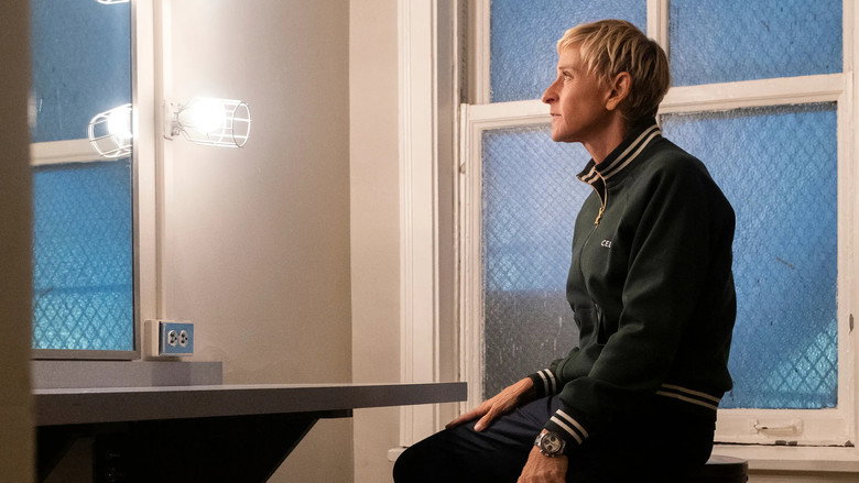 Ellen DeGeneres on stage at the Orpheum Theatre, bathed in warm light, her expression caught between a smile and something more complicated.