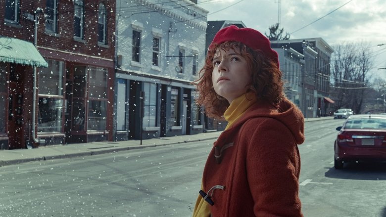 A dimly lit car interior, snow swirling outside the windshield, the faces of Jessie Buckley and Jesse Plemons half-lost in shadow.