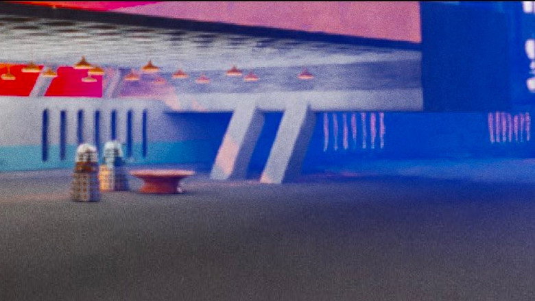 The Dalek’s eyestalk scans the empty corridors of a brutalist city, its single light casting long, sharp shadows.