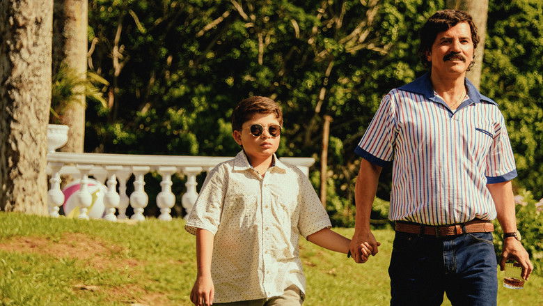 A young boy sitting at a large dining table, looking toward an empty chair at the head of the table.