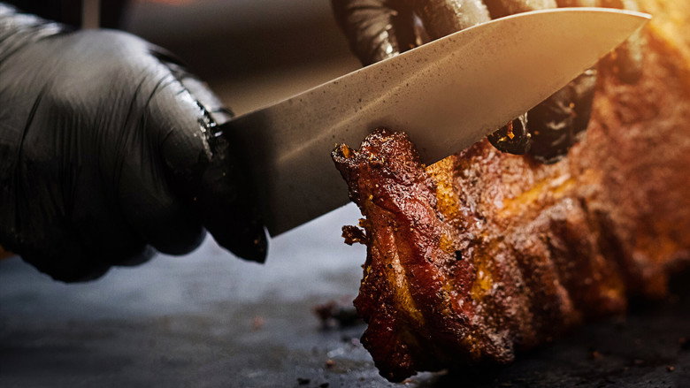 A slow-motion shot of smoke rising from a grill, the embers glowing like tiny stars against the dusk.