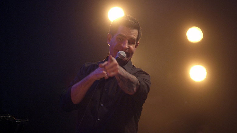 Todd Glass on stage, mid-gesture, his face caught between a grin and something more complicated