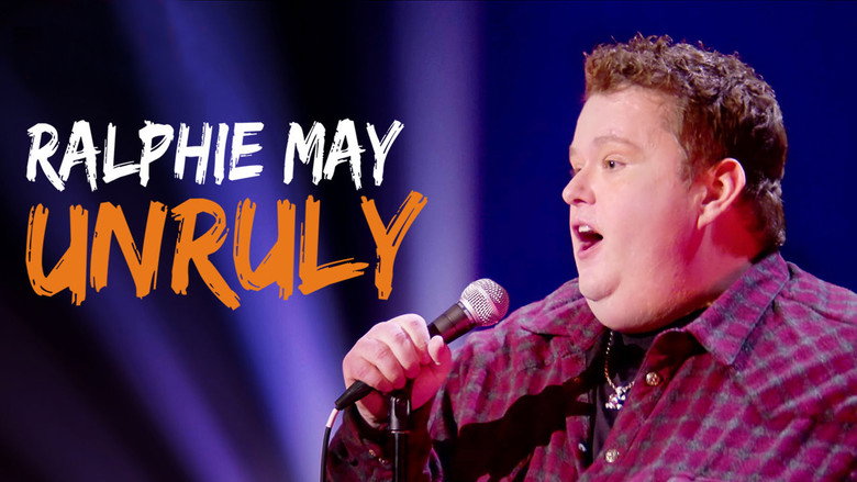 Ralphie May on stage, arms outstretched, commanding a packed theater with a raucous crowd