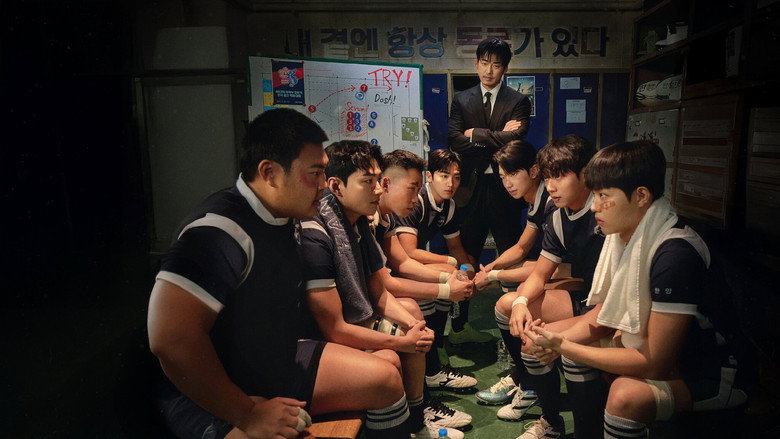 The team huddles under stadium lights, their faces half-lit by the glow of the field, exhaustion and determination etched into every line.