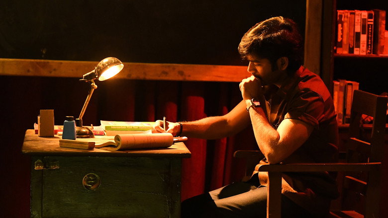 A classroom scene where Dhanush stands before a blackboard, his posture tense with frustration