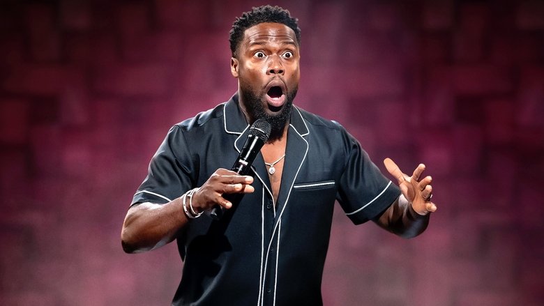 Kevin Hart in a hoodie, holding a pizza, mid-laugh in a warmly lit kitchen