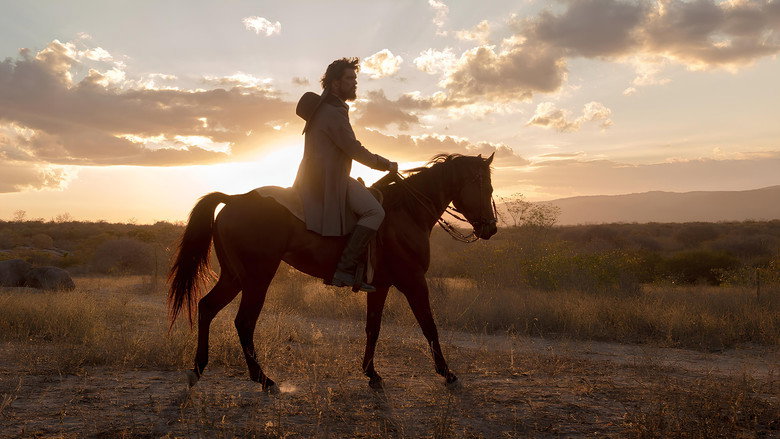 A lone rider on horseback, silhouetted against a vast, golden landscape