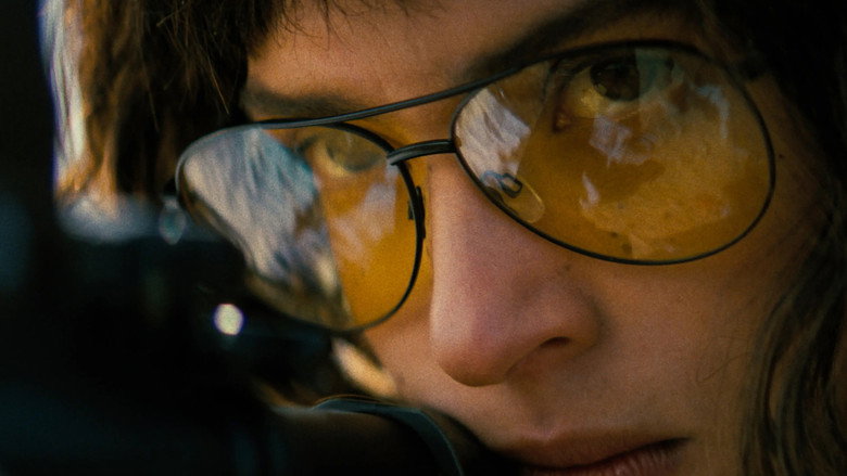 A sniper’s scope zeroes in on a distant figure, the desert heat warping the air between them.