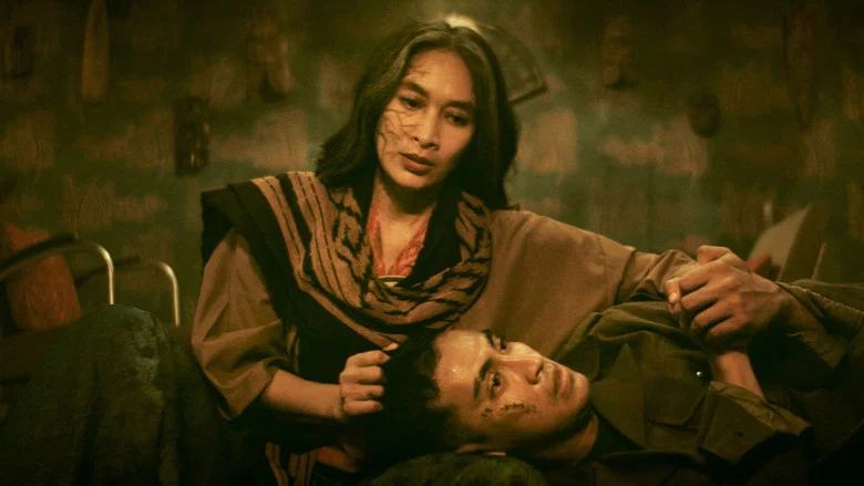 A dimly lit room where Vivian, the first wife, sits alone at a vanity, her reflection fractured in the mirror