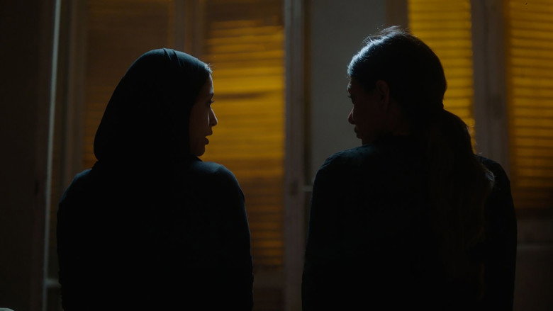 A dimly lit room where Kamla sits across from a patient, her expression a mix of professional detachment and quiet exhaustion.