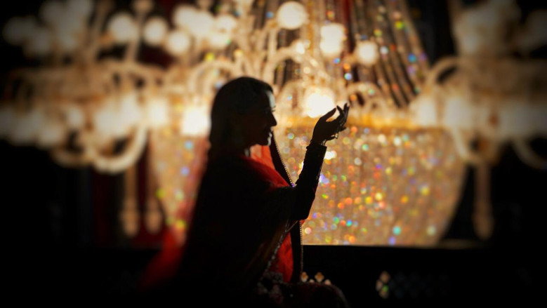 A dimly lit courtyard where Roop and Zafar first meet, the camera lingering on their clasped hands as the world around them blurs into a haze of lantern light