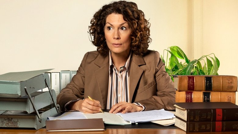 Helen Tudor-Fisk sits at her desk, surrounded by stacks of files, staring blankly at the camera as if to say, "What have I done?"