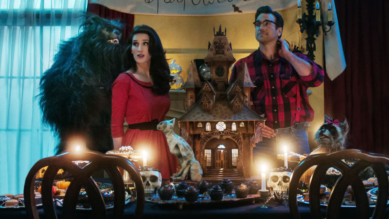 Christine McConnell stands in her dimly lit kitchen, surrounded by eerie desserts and gothic decor, her expression a mix of mischief and warmth.