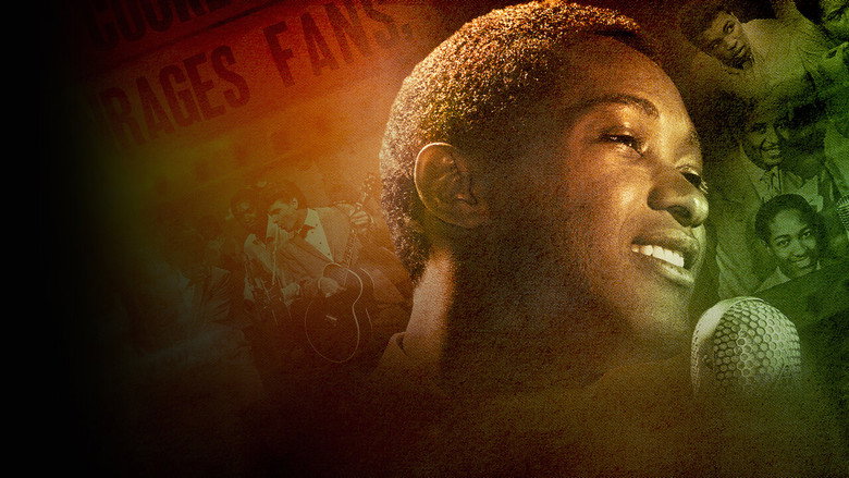 Sam Cooke performing on stage, bathed in soft light, his face half in shadow.