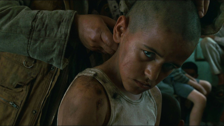 A child soldier having his head shaved while staring into the camera