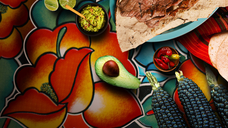 A vendor in Oaxaca ladles rich, dark mole onto a plate, the steam rising in slow motion against a backdrop of vibrant market stalls.