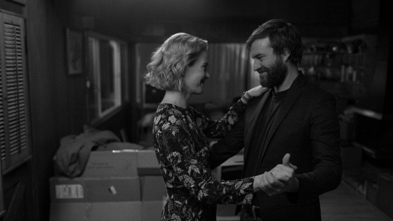 Jim and Amanda sit across from each other in a dimly lit diner, their faces half in shadow, the weight of years hanging between them.
