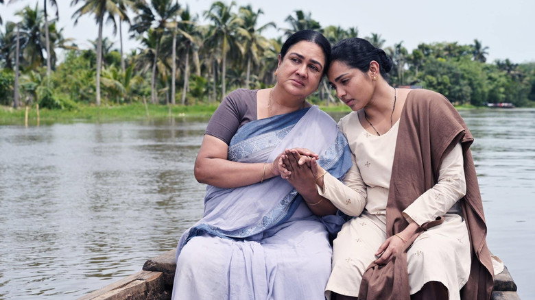 The flooded house, its reflection rippling in the water, as Leelamma and Anju sit in tense silence.