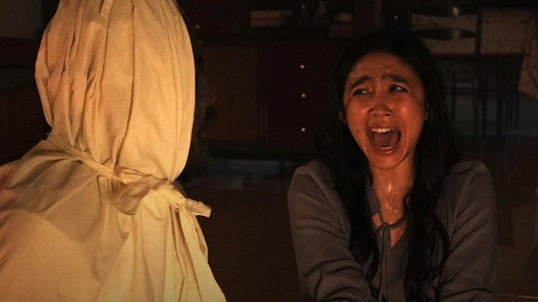 Farah kneels in prayer, her face half-lit by flickering candlelight, while shadows stretch unnaturally long behind her.