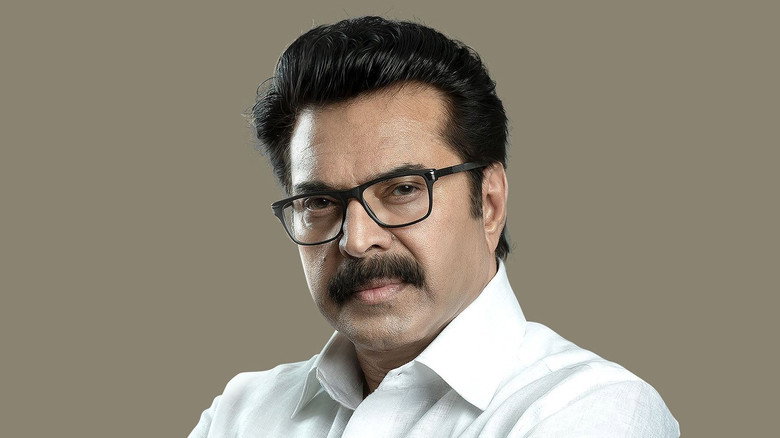 A lone figure in a white shirt stands on a balcony, overlooking a misty Kerala landscape, the weight of leadership pressing down on his shoulders.