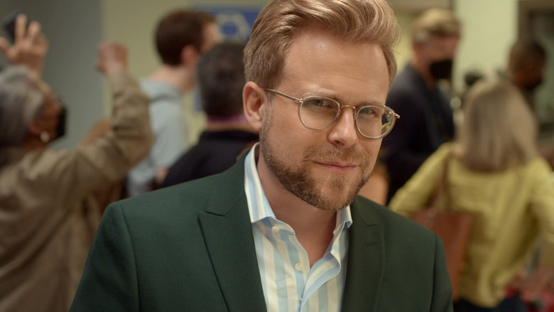 Adam Conover stands in a government office, arms crossed, looking skeptically at the camera while a bureaucrat in the background shuffles papers with exaggerated slowness.