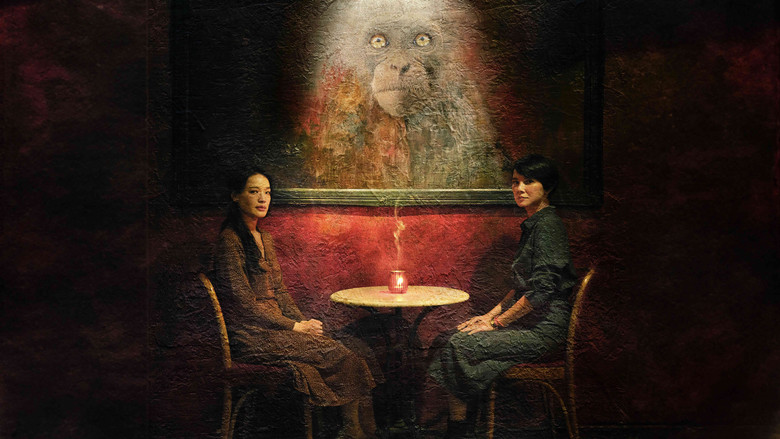 A dimly lit room where two women stand over a bloodied man strapped to a gurney, their faces half-lit by flickering candlelight