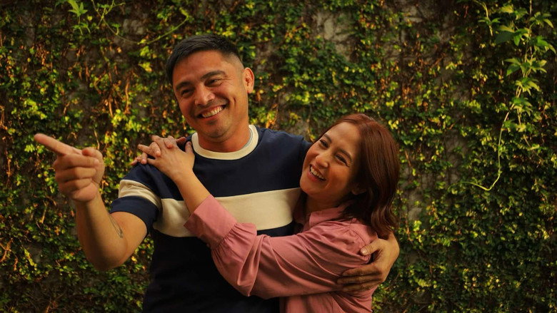 Joy and Ced sitting on a stone bench in Malta, the Mediterranean Sea stretching behind them, their expressions caught between laughter and something heavier