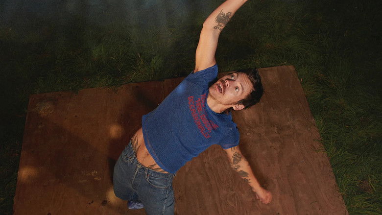 Harry Styles standing mid-stage, illuminated by a single, sharp spotlight, holding his guitar with a tense, focused grip.