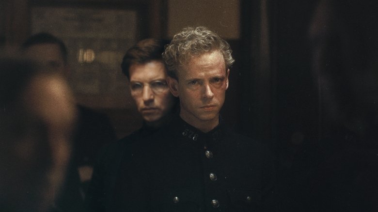 A dimly lit room where Wilfried Wils (Stef Aerts) sits at a table, his face half in shadow, the weight of his uniform pressing down on him.