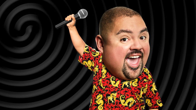 Gabriel Iglesias on stage, mid-laugh, arms outstretched as the audience blurs into a sea of faces.
