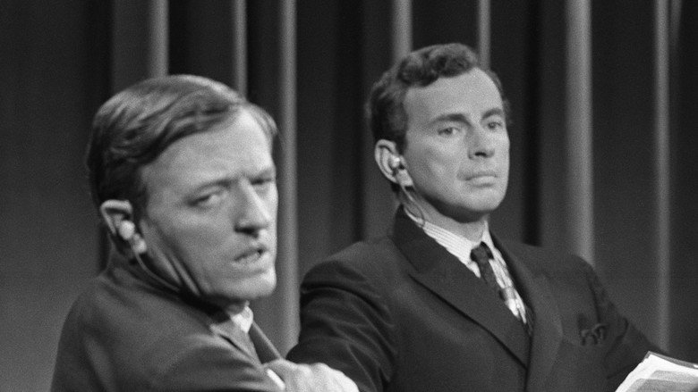 Vidal and Buckley face off in a tense 1968 debate, their expressions sharp with disdain