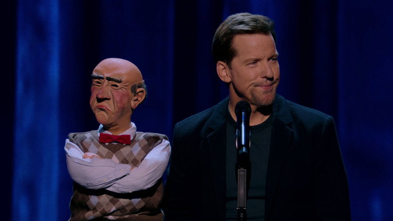 Jeff Dunham performing with Achmed the Dead Terrorist, a skeletal puppet with wild eyes and a turban, mid-joke in a packed arena.