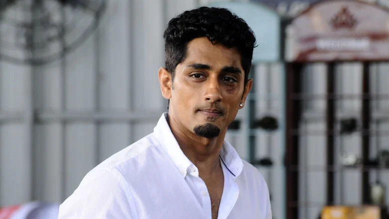 A neon-lit chase scene with Siddharth and Divyansha Kaushik in a car, the city blurring past in streaks of light