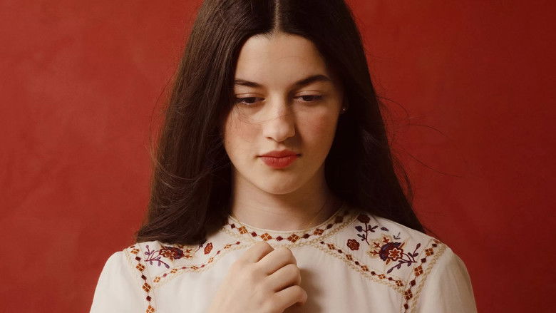 A young woman looking out a window, bathed in soft light