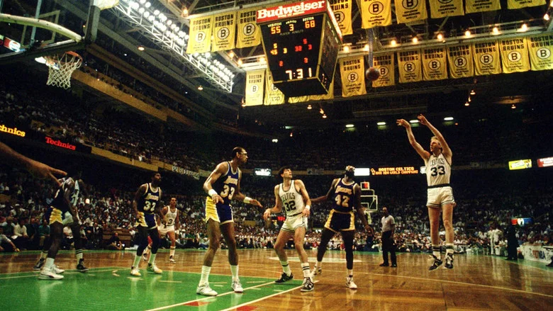 A black-and-white still of Larry Bird and Magic Johnson facing off, the tension between them palpable even in grainy footage.