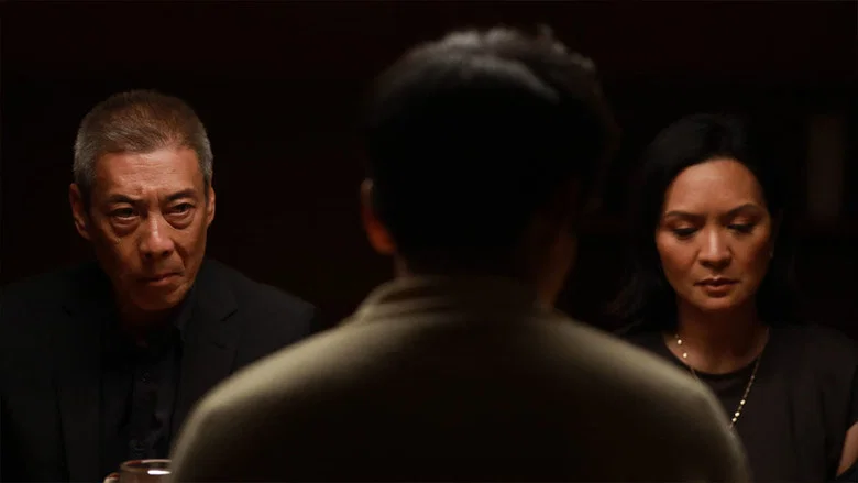 A dimly lit living room, the glow of a lamp casting long shadows, as a couple sits stiffly on a couch, their faces half-hidden in the half-light.
