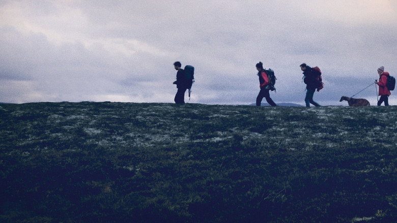 A family walks along a misty ridge, their backs to the camera, the landscape stretching endlessly ahead.