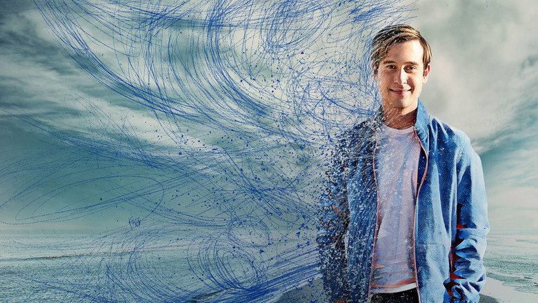 A dimly lit room where Tyler Henry sits across from a grieving woman, their hands nearly touching as he delivers a message from the beyond.