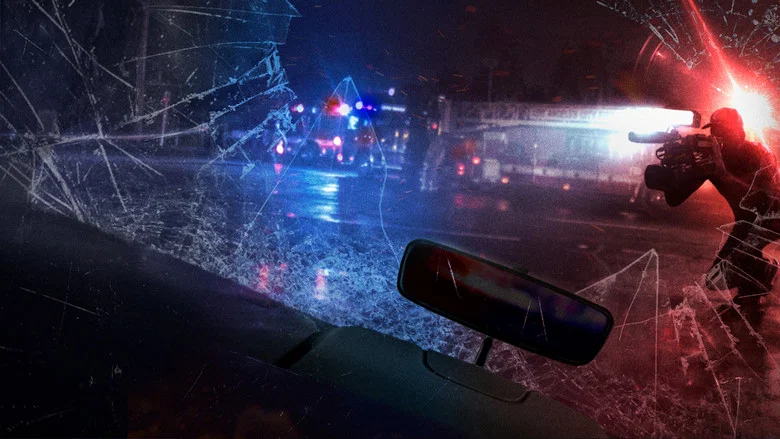 A stringer's camera captures the eerie glow of emergency lights at a crime scene, the night swallowing everything beyond the frame.