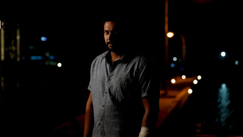 A close-up of Rahul Bose’s face, half-lit by a flickering streetlamp, his smile unnervingly wide.