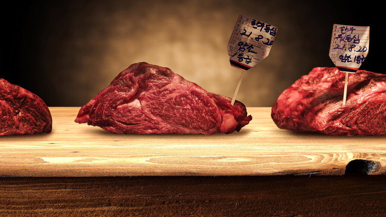 A close-up of marbled Hanwoo beef, its fat glistening under warm light