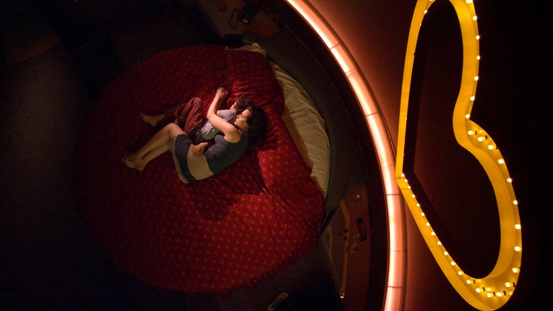 A woman and child sit in a dimly lit room, their faces half-hidden in shadow, the tension palpable in their stillness.