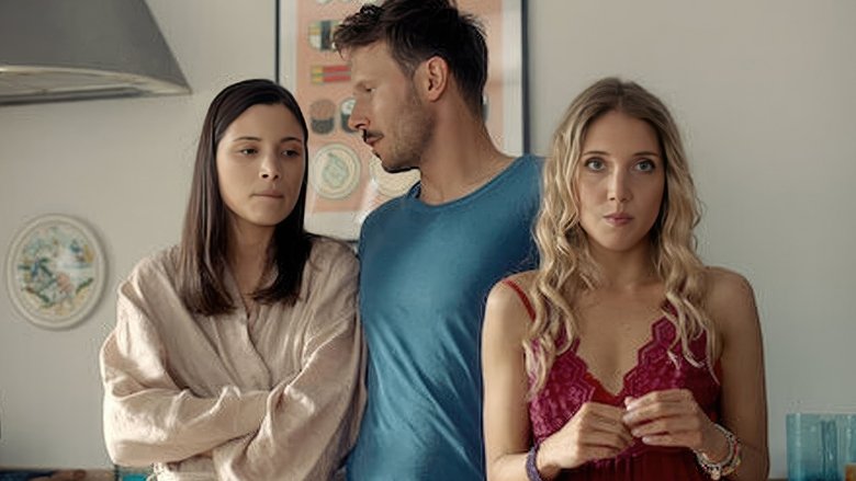 The couple stands in a sunlit kitchen, Monika holding a coffee cup while Enzo gestures wildly, his face a mix of exasperation and affection.