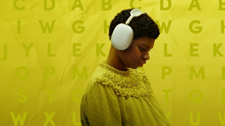 A close-up of Makayla Cain's hands hovering over a letter board, her facilitator's hand nearby, the room bathed in soft, golden light.